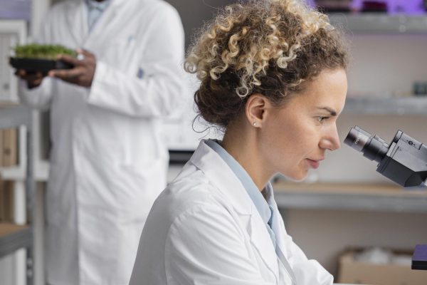 side-view-female-researcher-laboratory-with-microscope-male-colleague